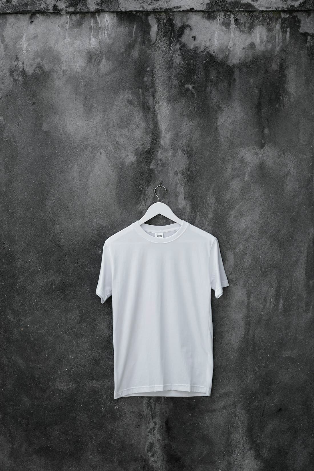 White t-shirt laid out against textured concrete in soft light